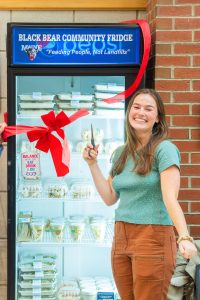 Student Kate Flynn cuts the ribbon for the Black Bear Community Fridge
