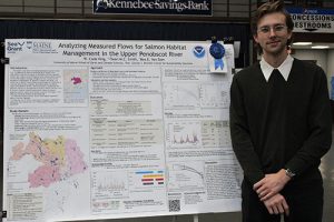 Cade King smiling beside his poster at the 2024 Maine Sustainability & Water Conference