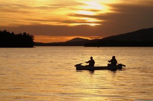 Two people paddling a canoe at sunset