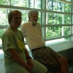 two faculty leaning back on a bench