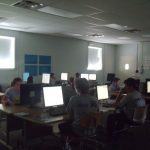 Students learning in front of a row of computers