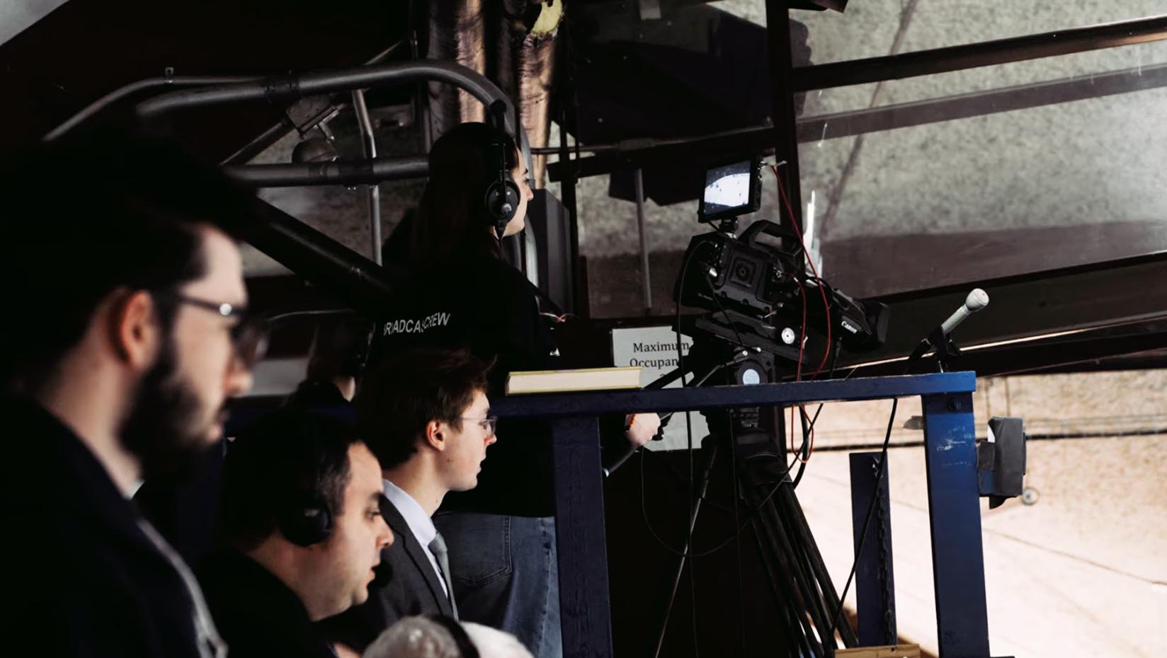 A photo of a student using a broadcast camera at a hockey game