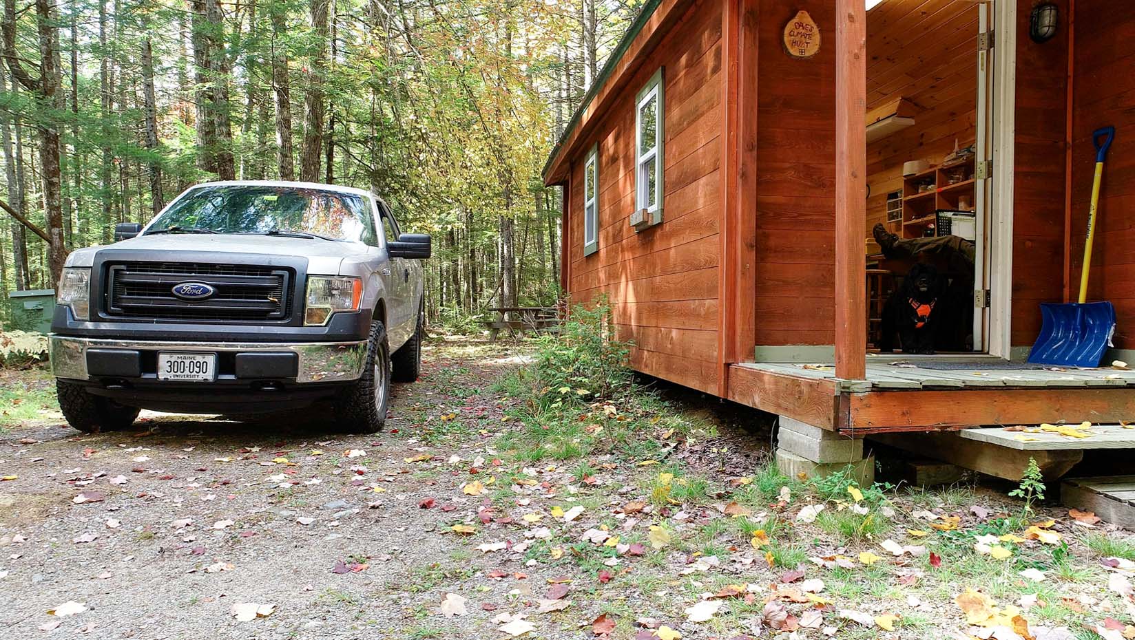 A photo of a truck parked next to a building in the woods