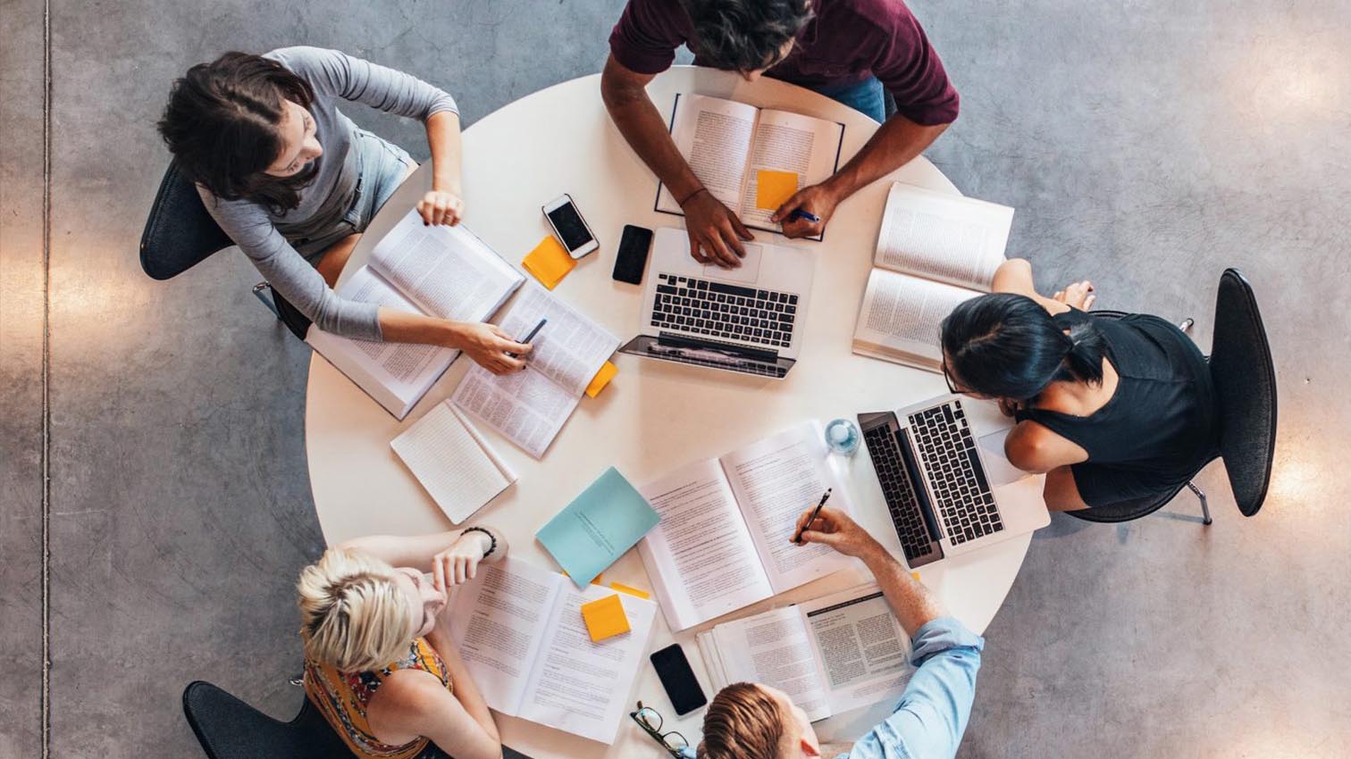 A photo of people sitting around a table, working.