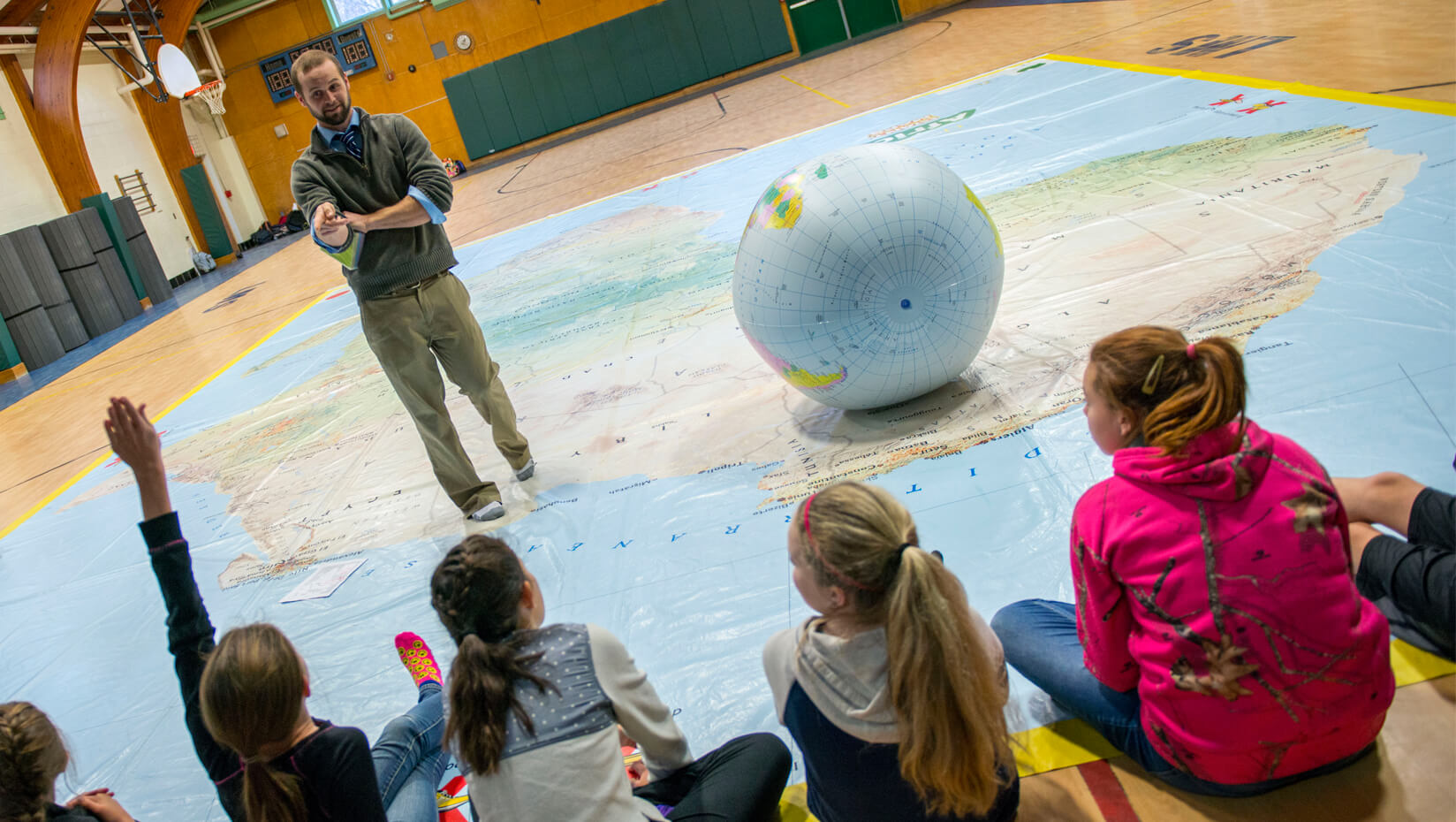 Middle school teacher Patrick Womac and students stand on giant map of Africa