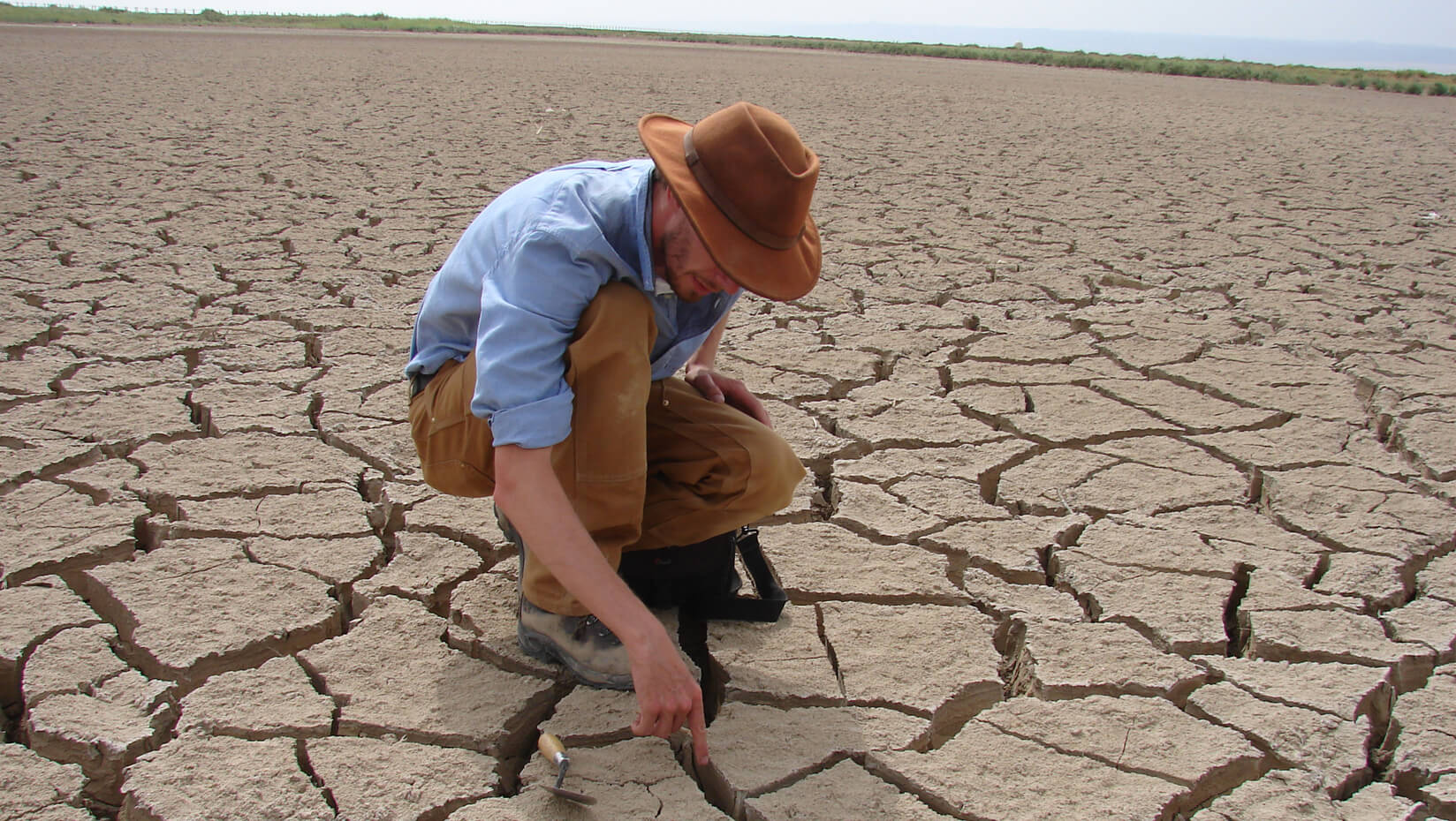 Aaron Putnam examining cracks in a desert