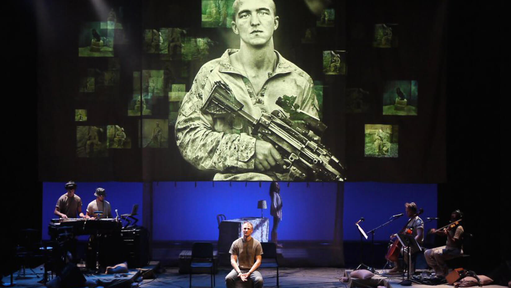 Man on stage with the image of a U.S. soldier behind him