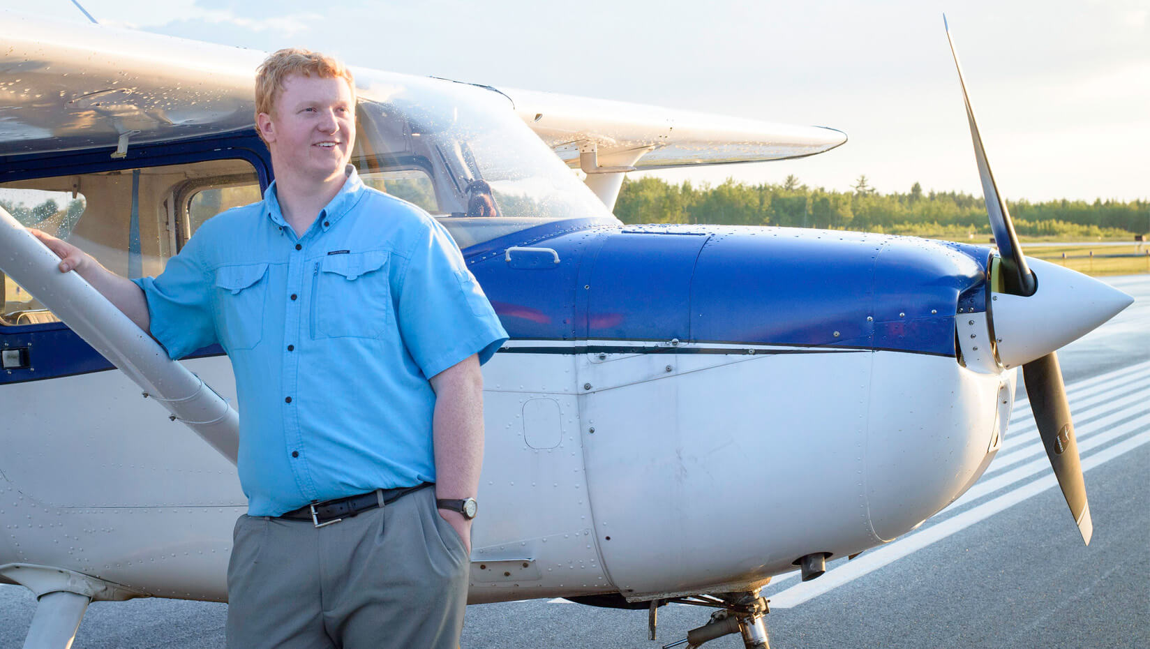 UMaine student stands in front of an airplane