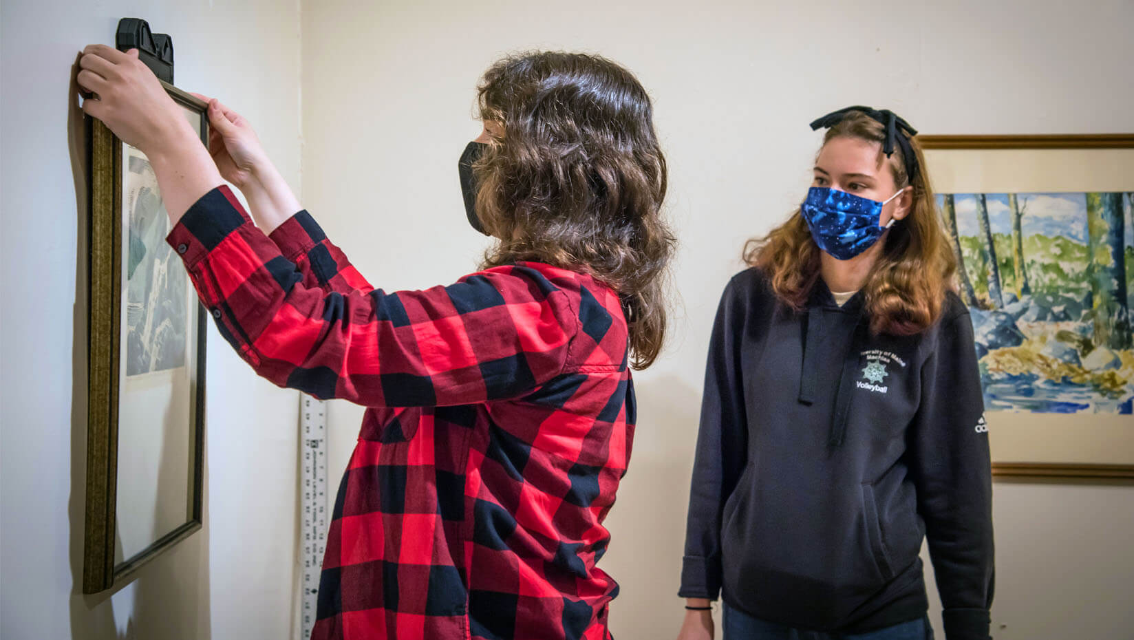 A student hangs artwork in UMM's art gallery