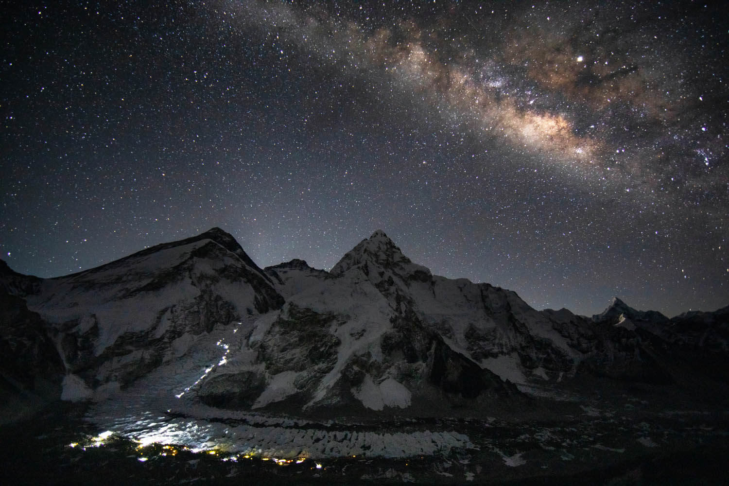 View of Mount Everest illuminated by the stars and climbers' lights