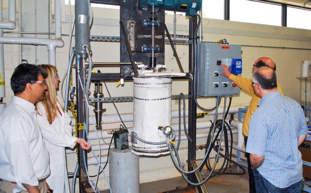 FBRI staff and a student stand around a batch reactor