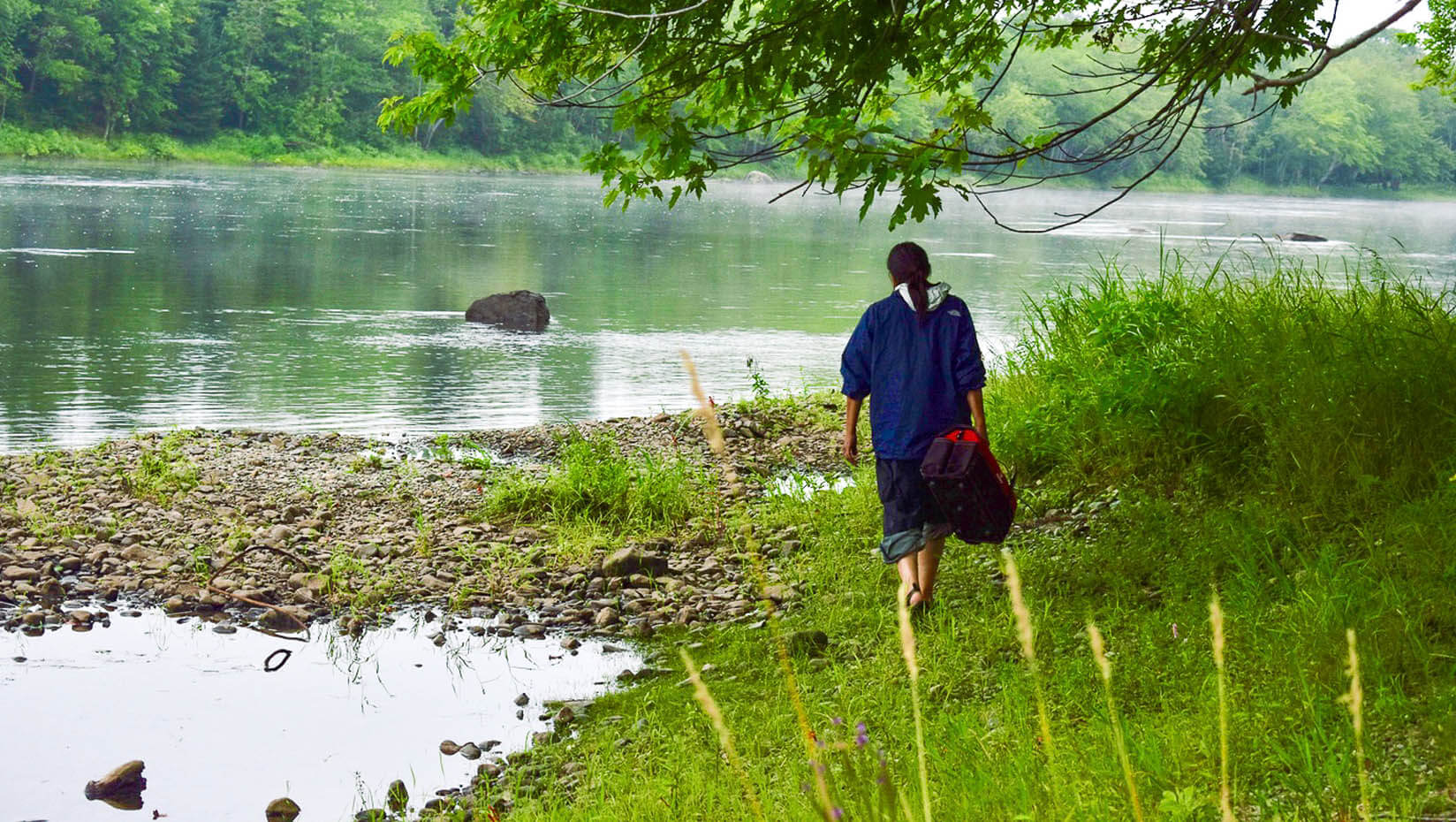 A person walks next to a river