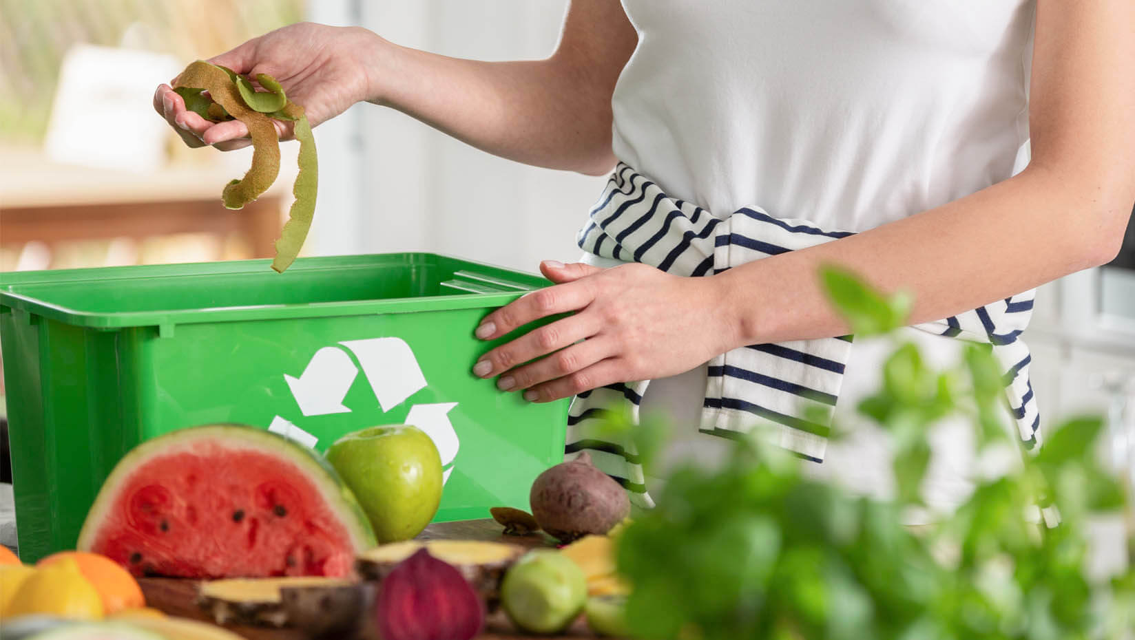 A woman puts food into a recycling container