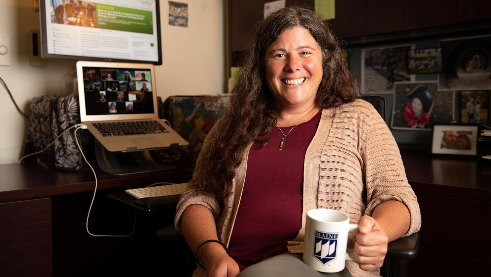 Erin Vinson sits in her office holding a UMaine coffee mug