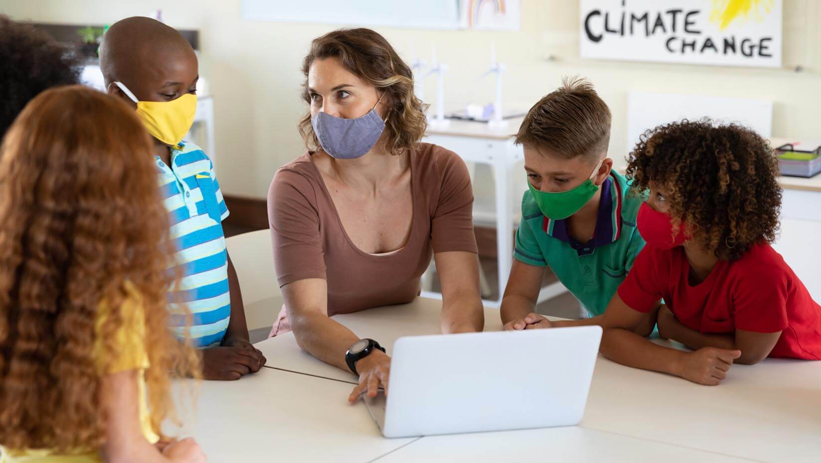Students and a teacher in a classroom, all wearing face masks