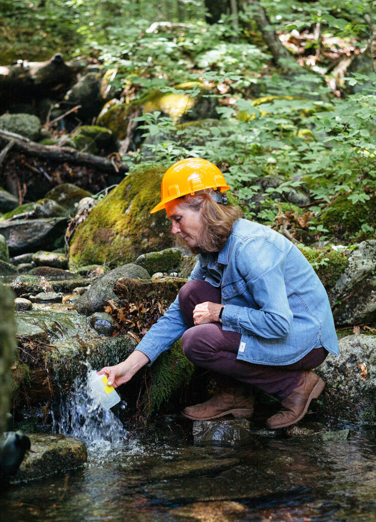 Woman collects water from stream