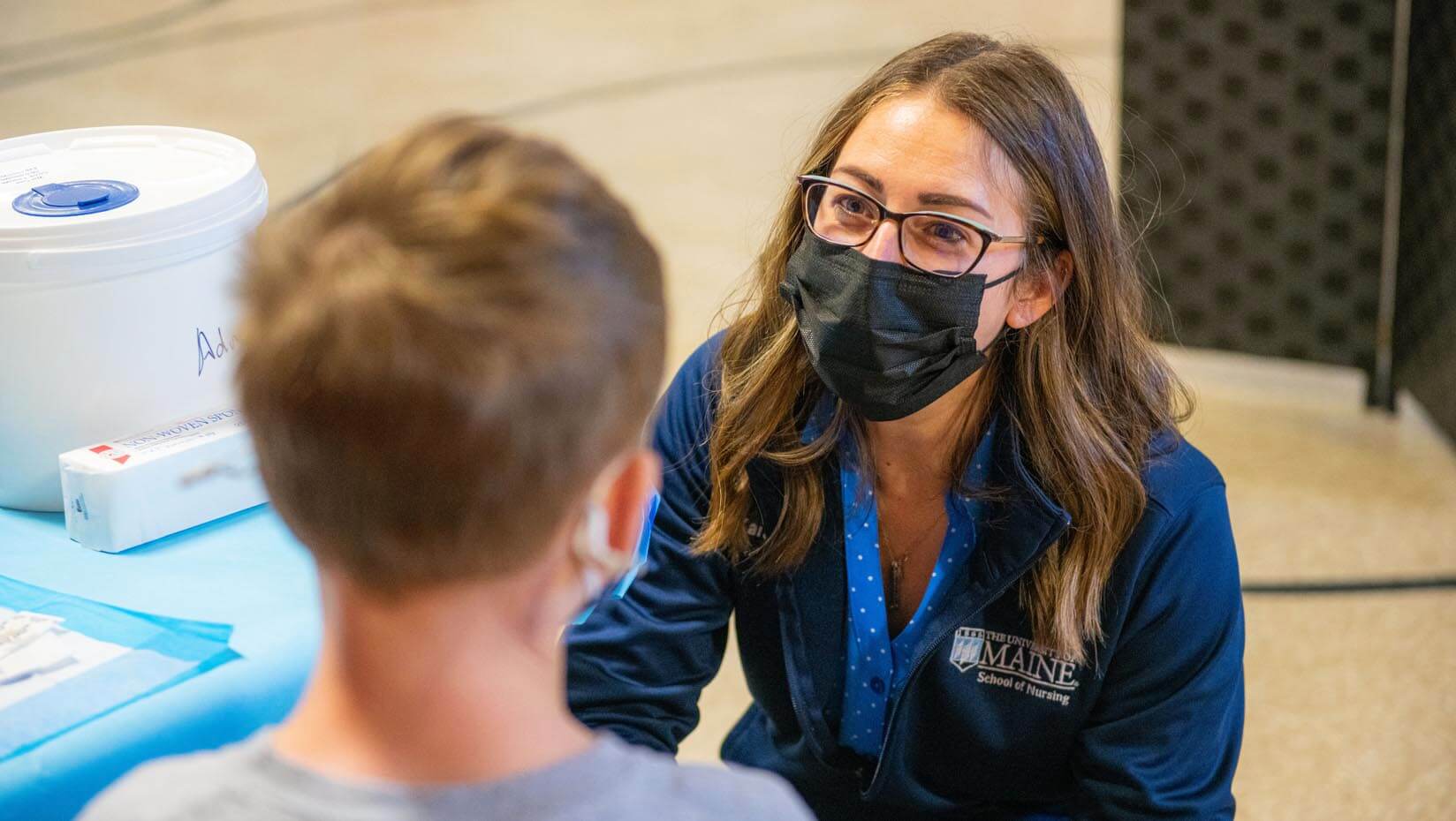 A photo of a UMaine faculty member talking to a vaccine recipient