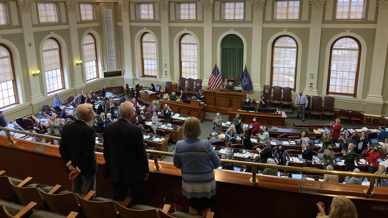 President Ferrini-Mundy, professor George Jacobson, and Maine Chamber of Commerce President Dana Connors standing in balcony of state house while Maine Legislature congratulates UMaine's attainment of R1 research classification