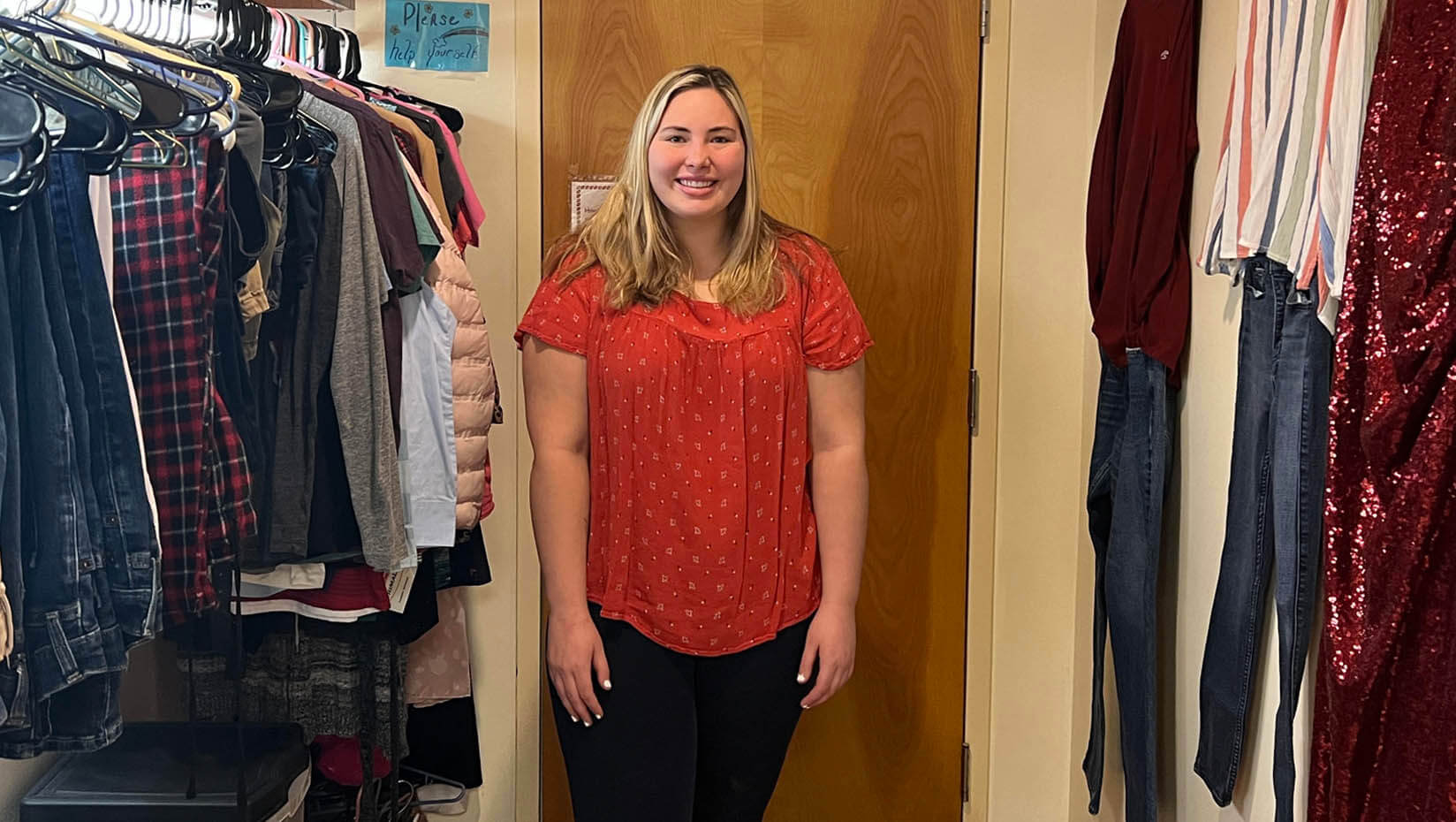 A photo of Janelle Goff standing with donated clothes