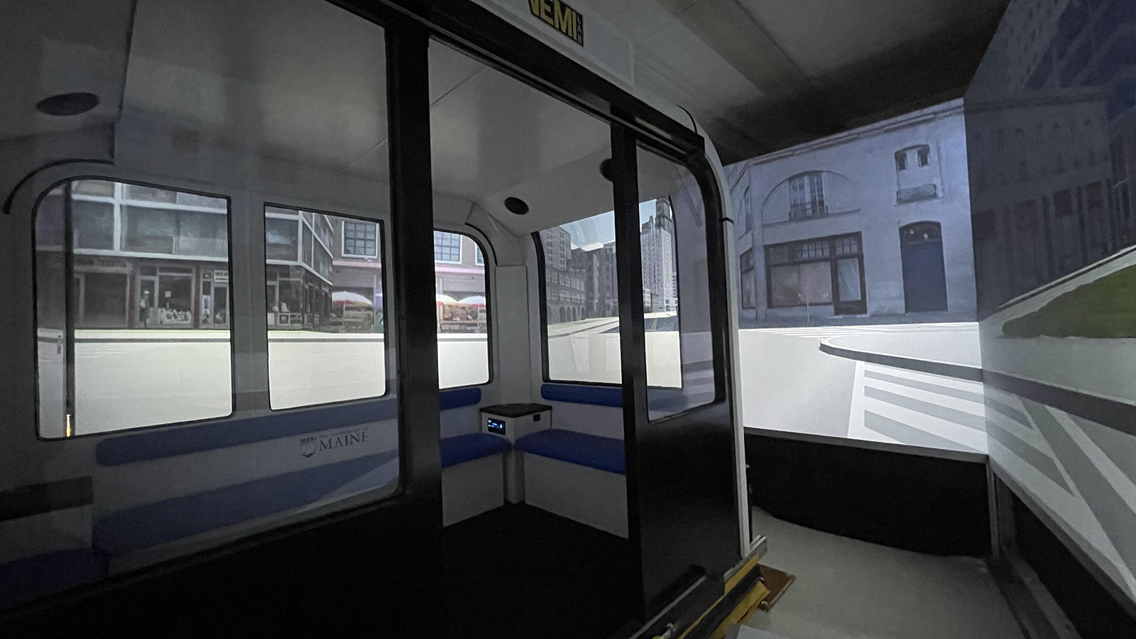 A full-size replica of an autonomous vehicle interior, in a room surrounded by screens simulating a street environment.