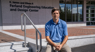 Justin Lapp sitting outside the Ferland Engineering Education and Design Center at the University of Maine