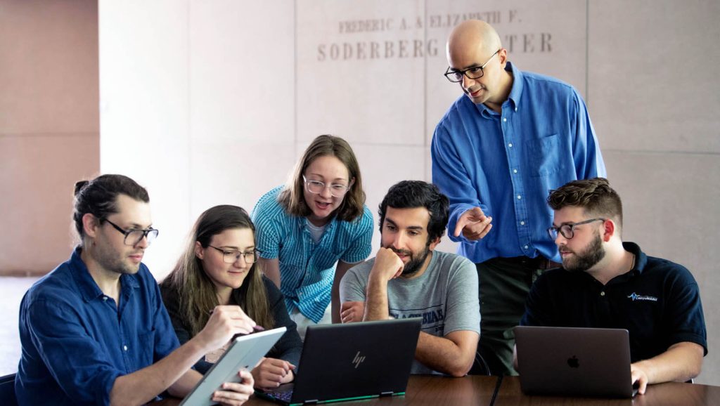 A photo of Andre Khalil and students looking at research data