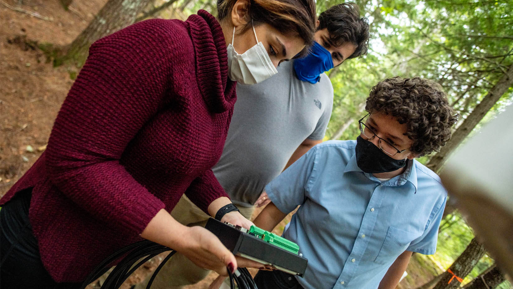 A photo of researchers looking at technology in a forest