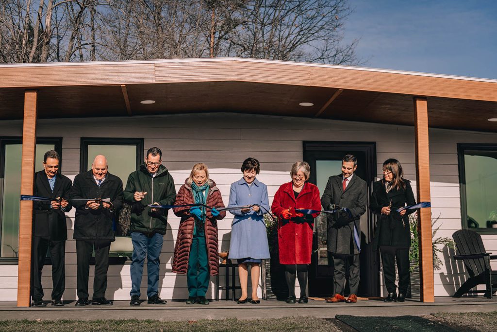 A photo of several people cutting a ribbon