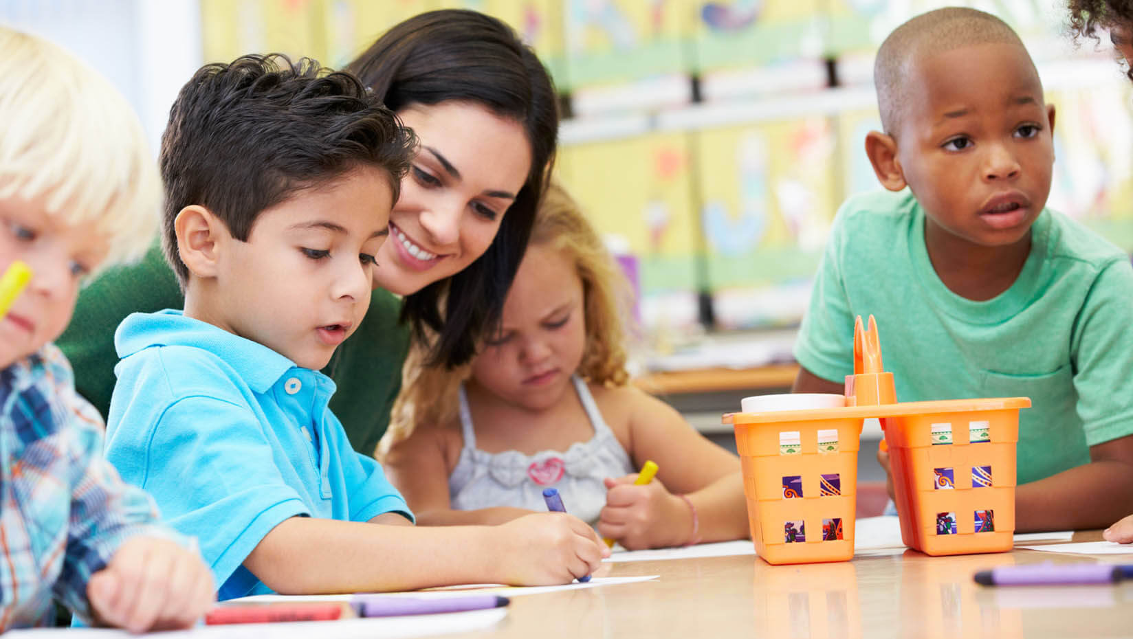 A photo of a teacher and young students in a classroom