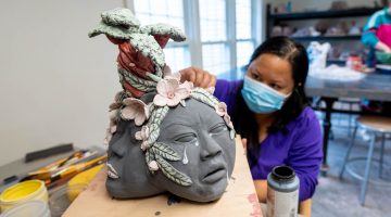 A photo of a masked student working on a ceramics project