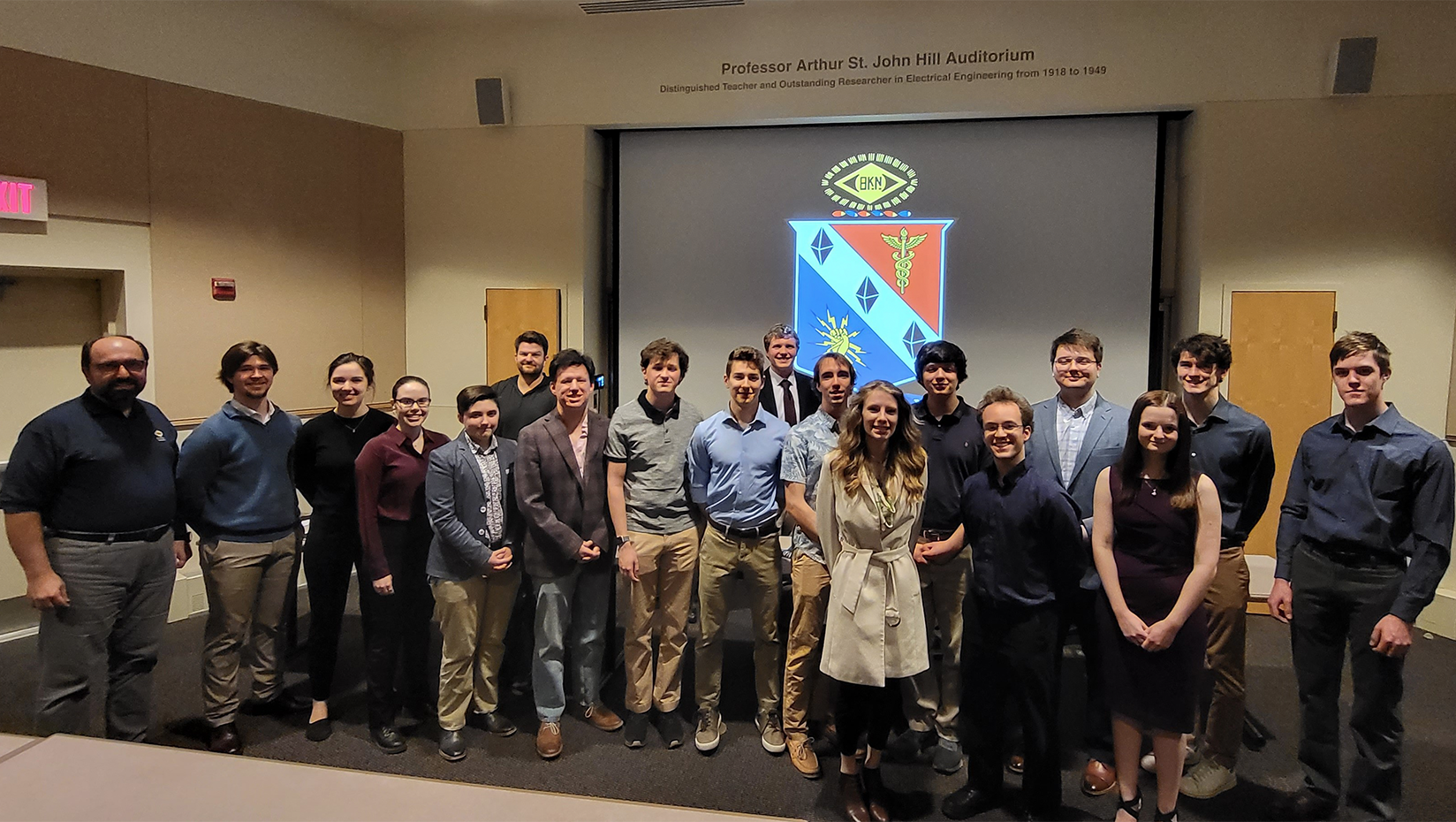 A group of people stand and pose for a picture at the front of an auditorium..