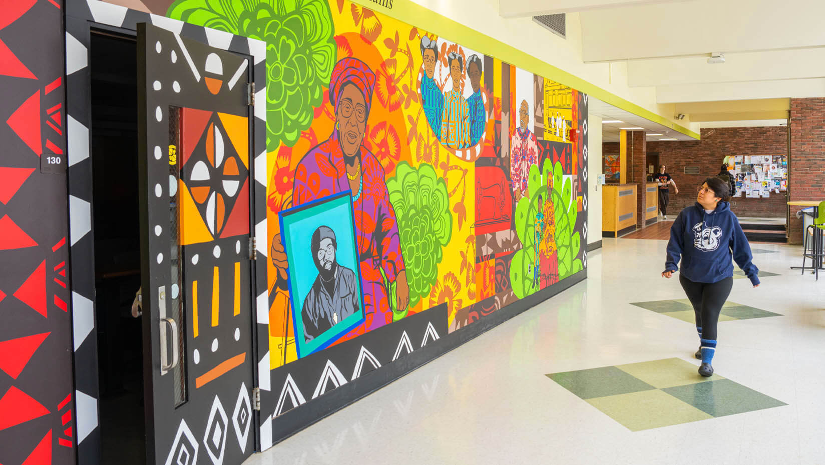 A photo of a person walking by the mural in Williams Hall