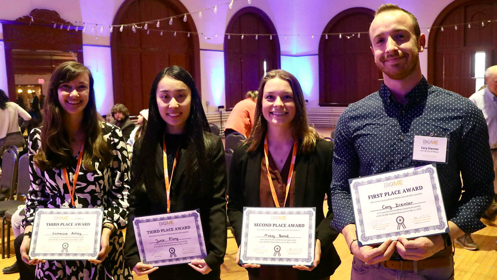 A photo of four people holding award certificates