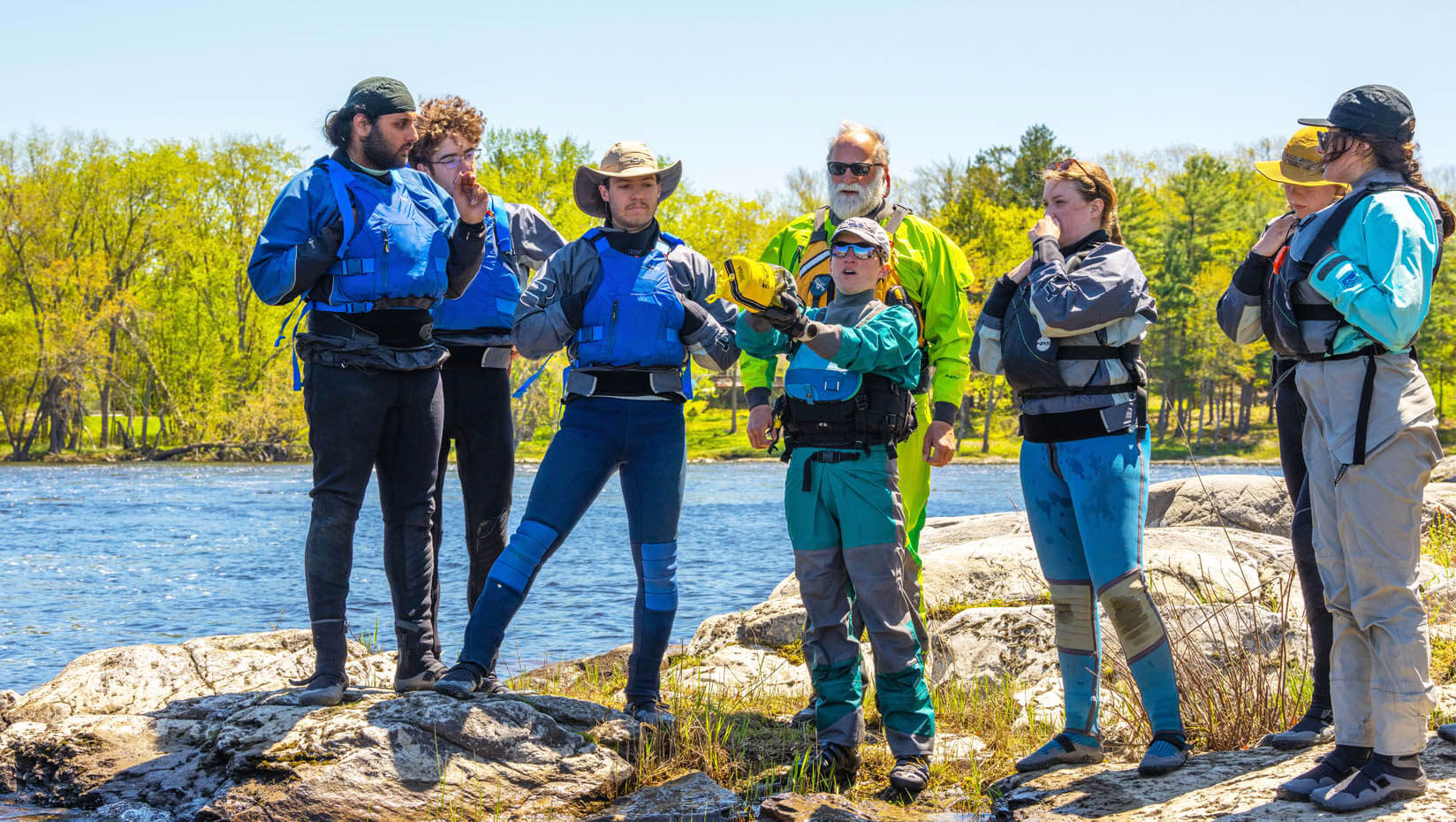 A photo of a class of students standing on the edge of a river