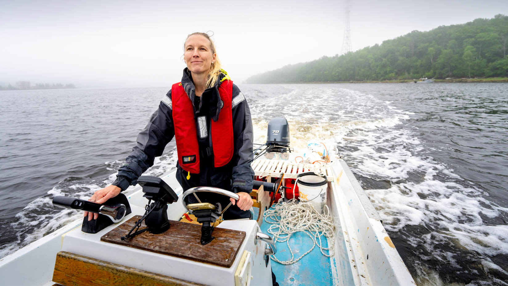 A photo of Lauren Ross steering a boat on the Maine ocean