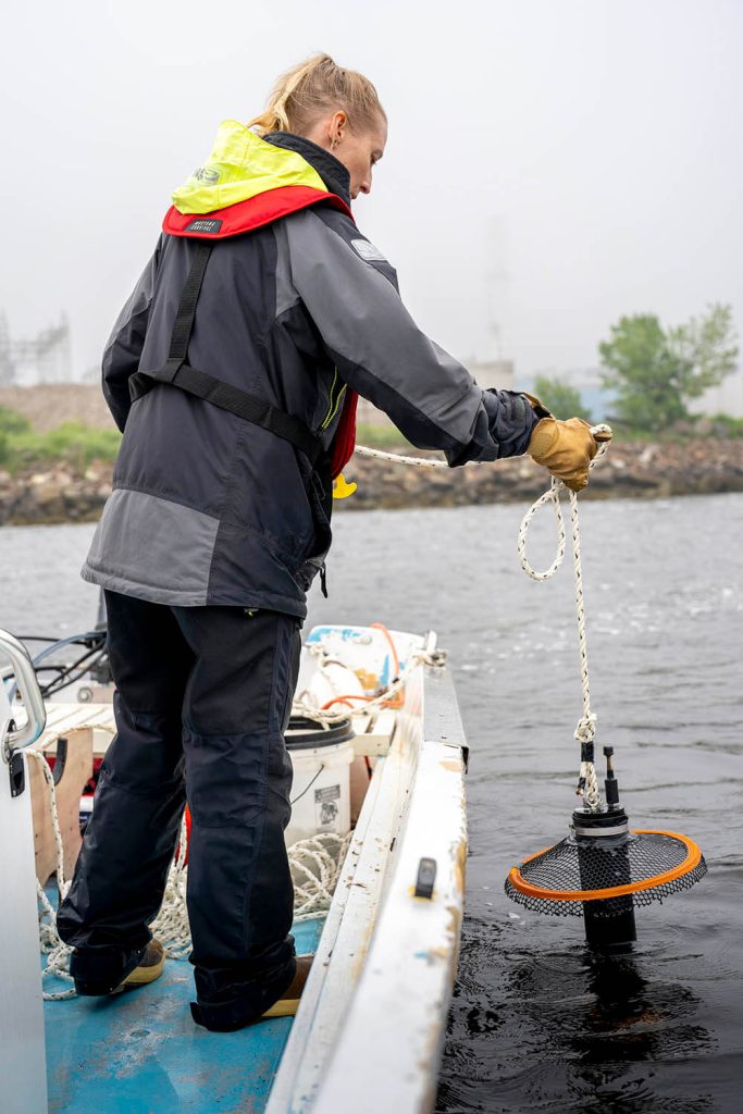 Foto de Lauren Ross bajando un instrumento científico al costado de un bote
