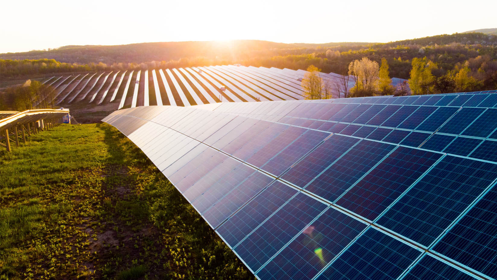 A photo of an array of solar panels in a field at sunset