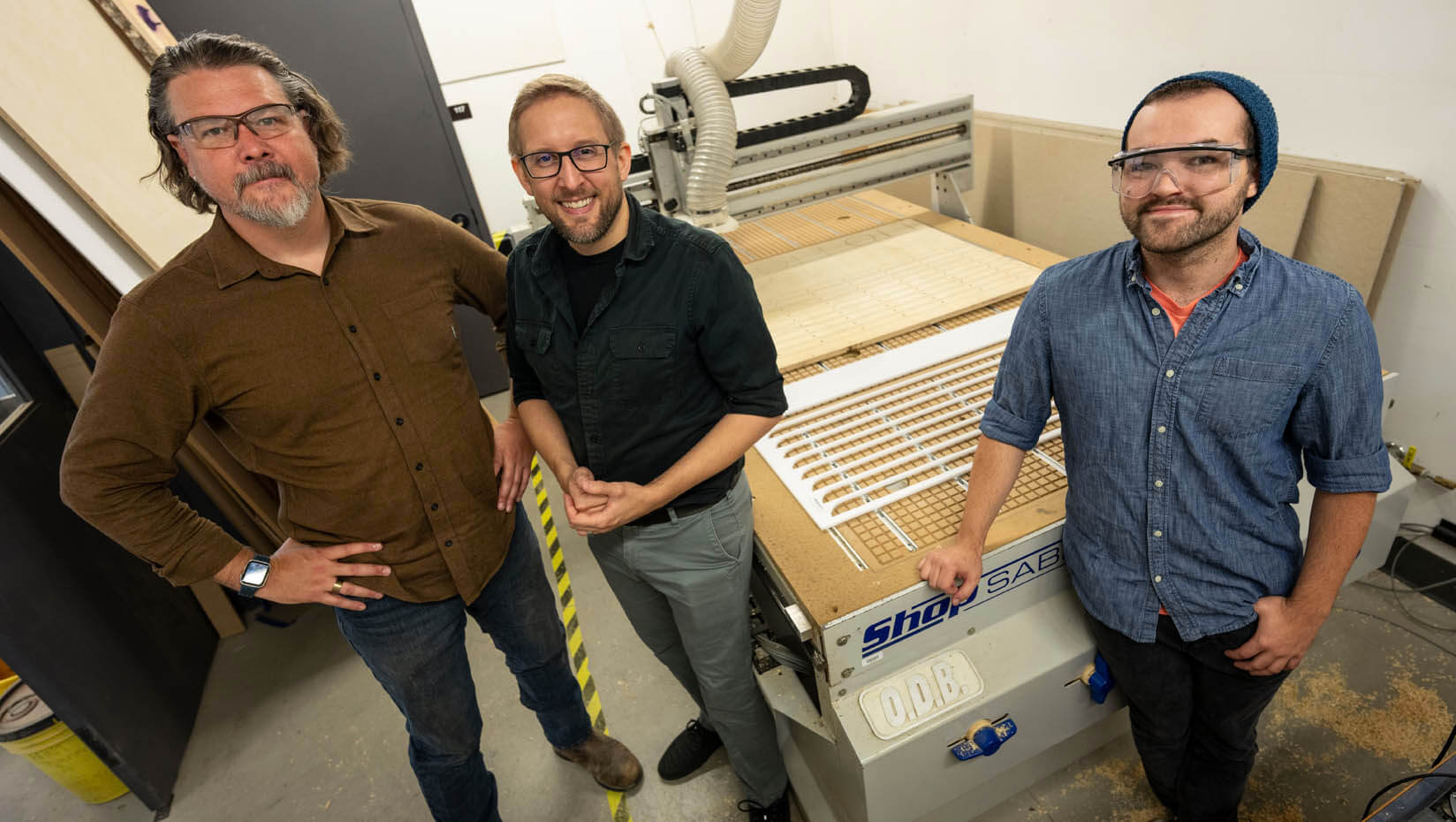 A photo of three people in front of machinery