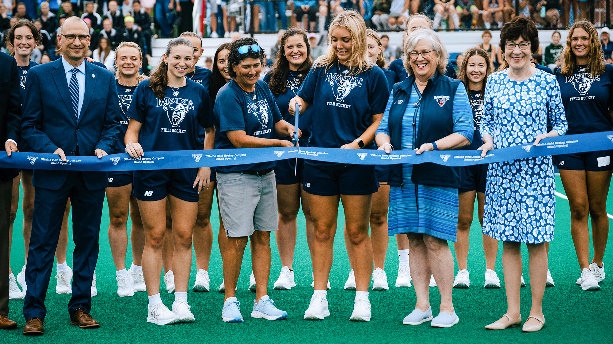 A photo of people cutting a ribbon at the new field hockey facility at UMaine