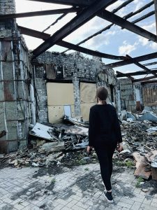 A photo of Vita Tomakhiv looking at rubble in Ukraine