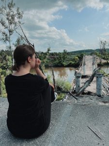 A photo of Vita Tomakhiv looking at rubble in Ukraine