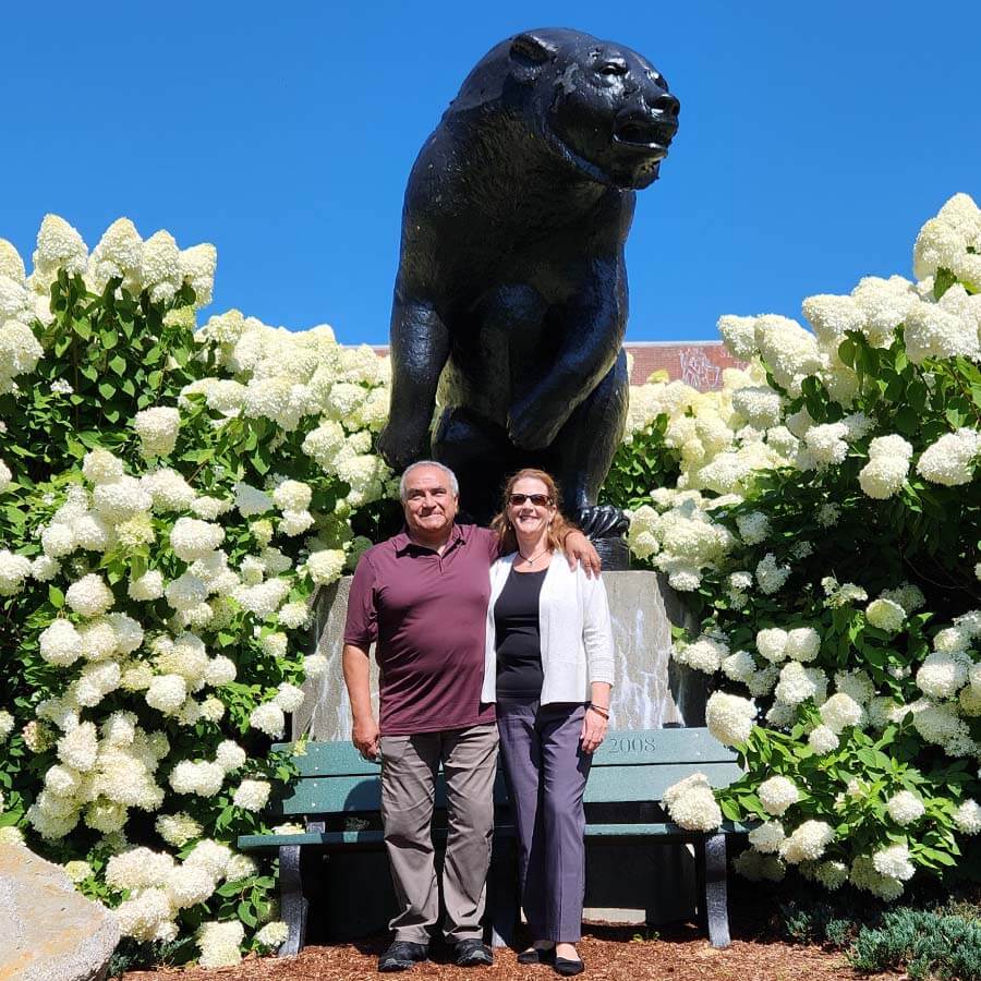 A photo of Hector Martinez and Jolayne Houtz standing in front of UMaine's bear statue