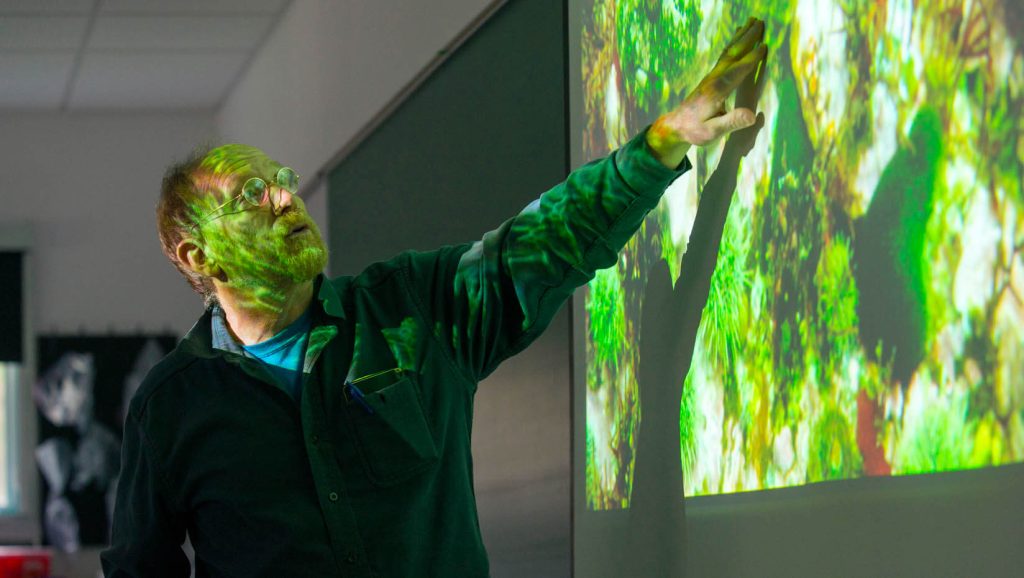 A photo of Bob Steneck teaching in front of a projector screen