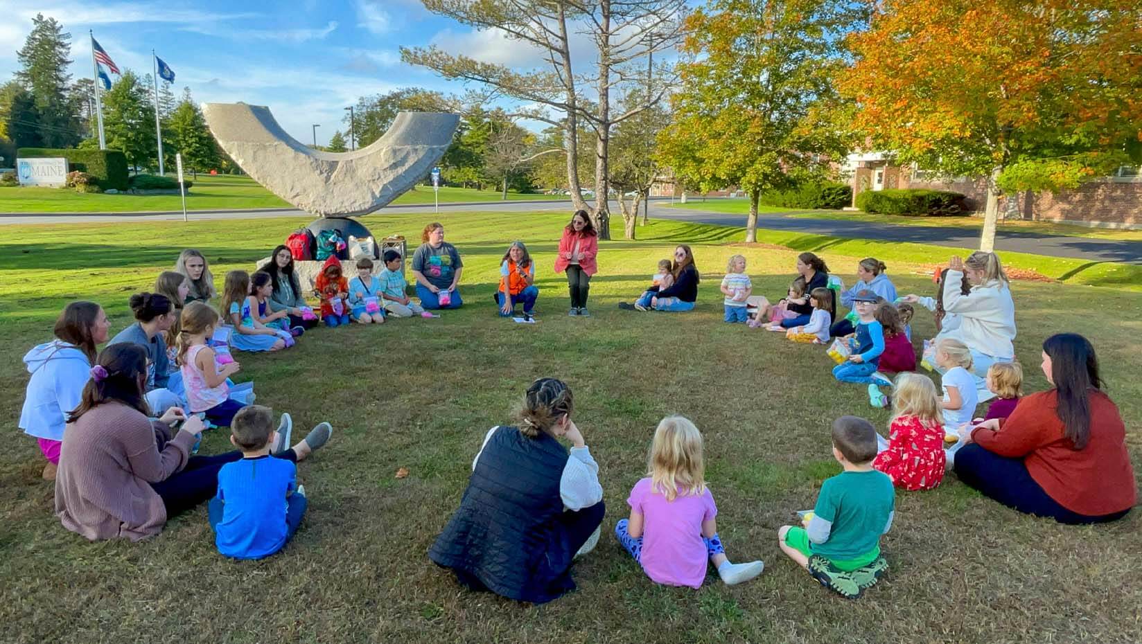 A photo of program participants sitting in a circle on a green lawn