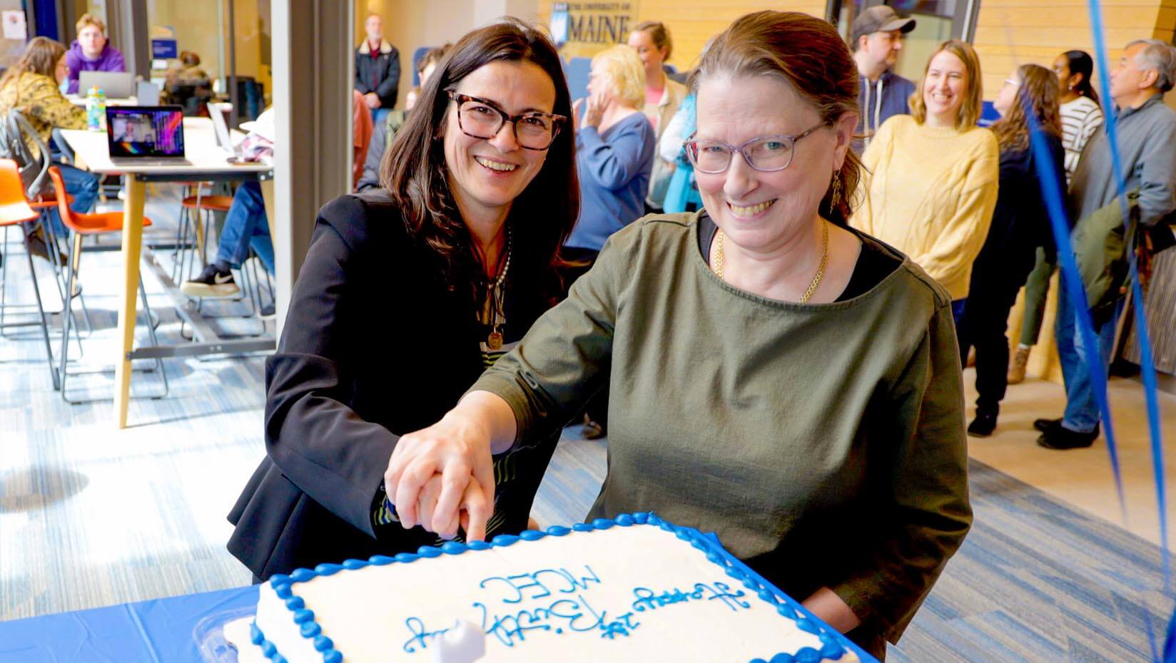 A photo of two people cutting a cake