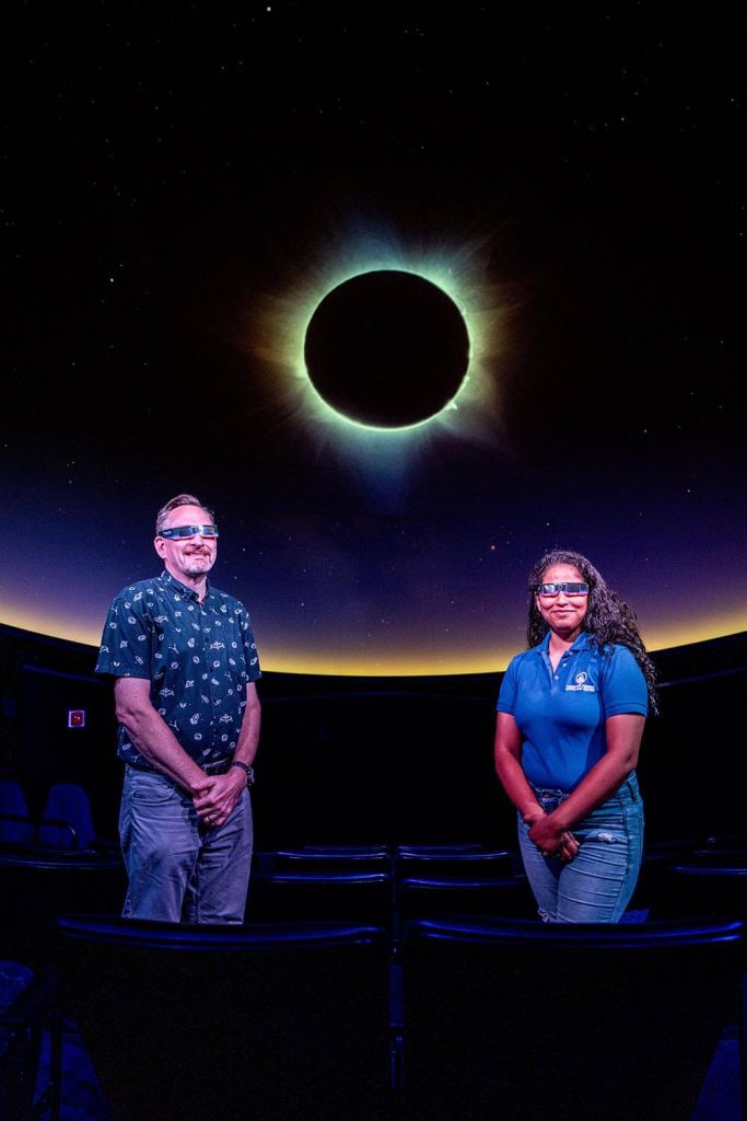 A photo of Shawn and Nikita standing in front of an Eclipse projection