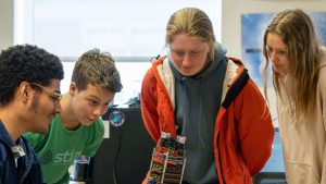 A photo of students looking at a nanosatellite