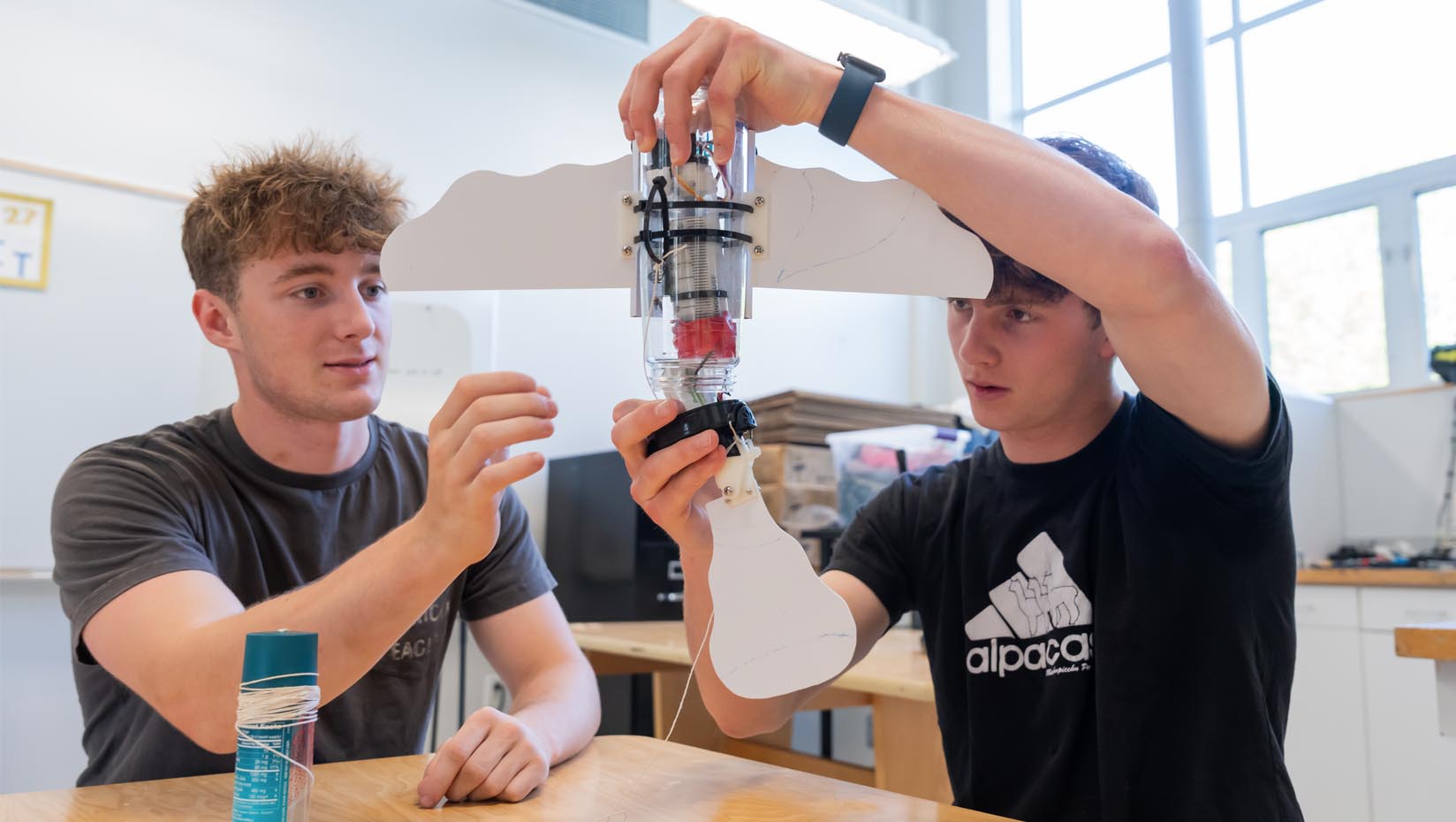 A photo of two students holding a robotic device