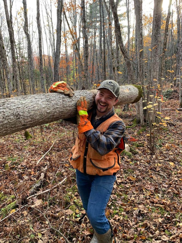 A photo of Tyler Everett holding an ash log