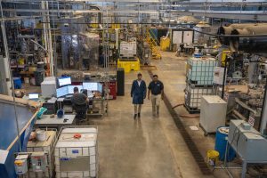 A photo of two people walking through a lab